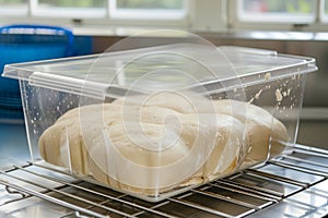 dough rising in a clear plastic proofing box on a rack