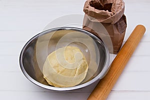 Dough with rolling pin, flour on white background