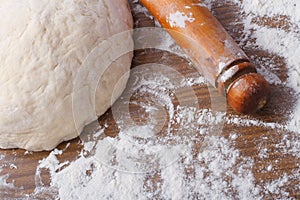 Dough with rolling pin on floured table