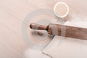 Dough, rolling pin, half of lemon and flour sprinkled on a light