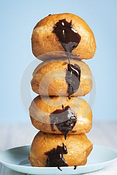 Doughnuts stack on a blue plate. Chocolate Berliner donuts tower