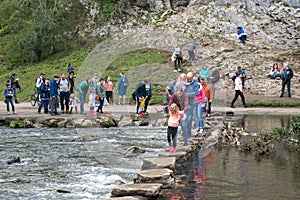 Tourists crossing  the famous stepping stones at Dove Dale`s stepping stones