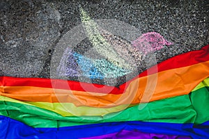 Dove of peace painted with chalk on the street, under it the rainbow flag