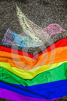 Dove of peace painted with chalk on the street, under it the rainbow flag