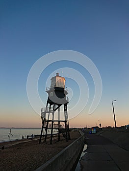 Dovercourt lighthouse at dusk as the sun sets on Harwich Harbour with a crescent moon above