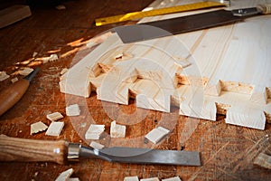 Handmade dovetail joints in furniture workshop. Chisel and saw on table. photo