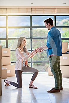 Down on bended knee. a young woman proposing to her boyfriend while moving house.