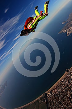 Down. Freedom as a way of life. Extreme people flying in open air. Parachutist in green suit. Skydiver is in free fall.