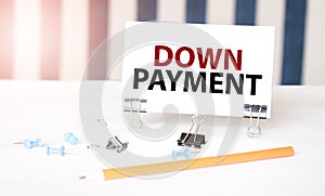 DOWN PAYMENT sign on paper on white desk with office tools. Blue and white background