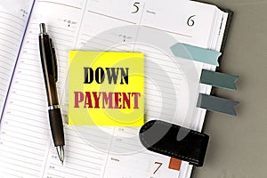 DOWN PAYMENT word on the yellow sticky with office tools on daily planner