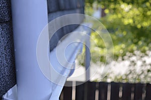 A down spout pipe leading to an eavestrough installed below a roof ledge.