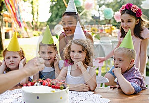 Down syndrome child with friends on birthday party outdoors in garden.