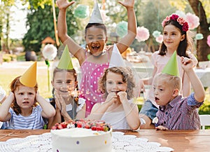 Down syndrome child with friends on birthday party outdoors in garden.