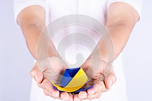 Down syndrome day, hands holding blue yellow ribbon awareness support patient with illness disability