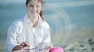 Down syndrome girl playing on touchscreen tablet on beach