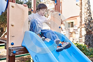 Down syndrome kid playing on slide at park