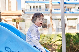 Down syndrome kid playing on slide at park