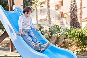 Down syndrome kid playing on slide at park