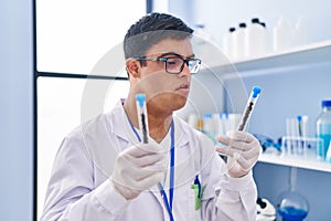 Down syndrome man wearing scientist uniform holding test tubes at laboratory