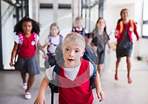 A down-syndrome school boy with group of children in corridor, running.