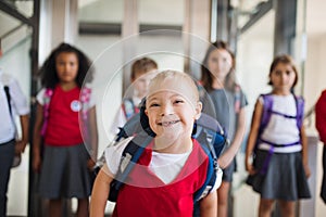 A down-syndrome school boy with group of children in corridor, walking.