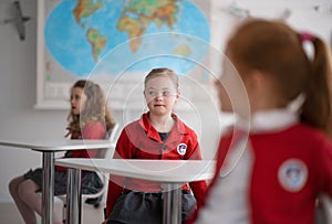 Down syndrome schoolgirl paing attention in class at school, integration concept.