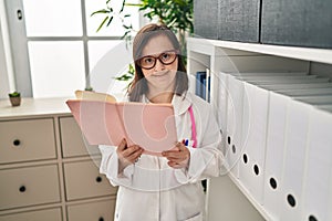 Down syndrome woman wearing doctor uniform reading book at clinic