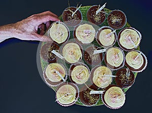 Down view of chocolate and vanilla cup cakes with a hand taking one