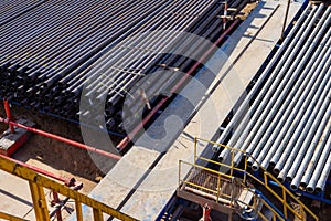 Down view through Rig floor stairs to pipes on pipe rack next to catwalk. Looking up derrick at pipes in a rack on an offshore oil