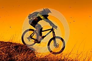 Downhill mountain bike rider at sunset