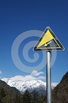 Downhill road sign with snow mountains