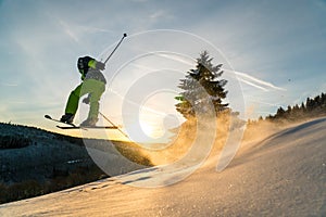 Downhill skier jumping in powder snow and sunset conditions