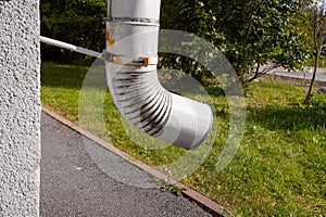 Downpipe on house wall against asphalt and grass