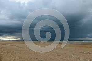A downpour over the English Channel and Ouistreham beach in Europe, France, Normandy, in summer, on a sunny day
