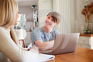 Downs Syndrome Man Sitting With Home Tutor Using Laptop For Lesson At Home