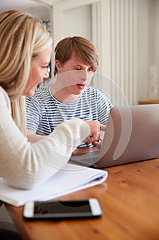 Downs Syndrome Man Sitting With Home Tutor Using Laptop For Lesson At Home