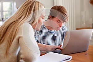 Downs Syndrome Man Sitting With Home Tutor Using Laptop For Lesson At Home photo