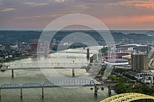 Downtown district of Cincinnati city in Ohio, USA at sunset with driving cars traffic on bridge and brightly illuminated