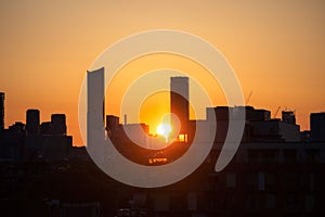 Downtown Toronto at sunrise, with warm golden light in the sky behind silhouettes of the skyline buildings