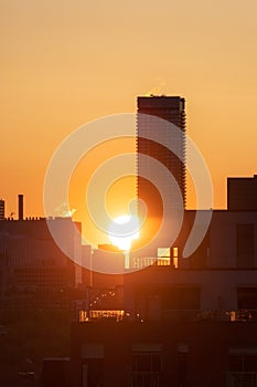 Downtown Toronto at sunrise, with warm golden light in the sky behind silhouettes of the skyline buildings