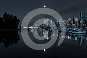 Downtown vancouver canada on a clear night with a full moon reflection