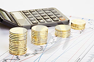 Downtrend stacks of coins, a calculator on the financial chart.