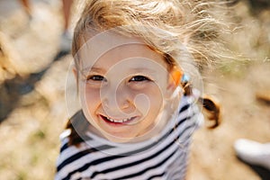 Downward angle portrait of joyful little girl in a sunny day