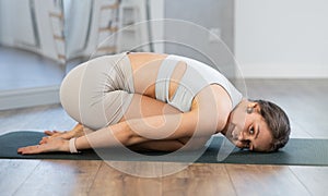 Downward facing dog yoga pose - young girl doing yoga in fitness studio