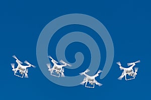 Dozens of drones swarm in the blue sky. Quadcopters drones with digital camera in the air over city. New technology in the aero