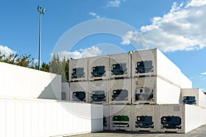 Dozens of immaculate white refrigerated containers stacked in the sunlight in an industrial park