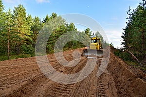 Dozer during clearing forest for construction new road . Yellow Bulldozer at forestry work Earth-moving equipment at road work,
