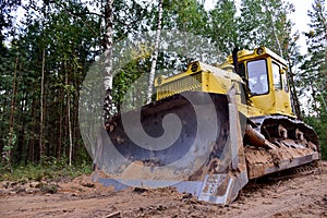 Dozer during clearing forest for construction new road . Yellow Bulldozer at forestry work Earth-moving equipment at road work,