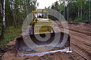 Dozer during clearing forest for construction new road . Yellow Bulldozer at forestry work Earth-moving equipment at road work,