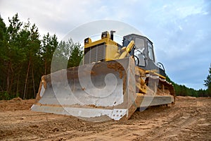 Dozer during clearing forest for construction new road . Yellow Bulldozer at forestry work Earth-moving equipment at road work,